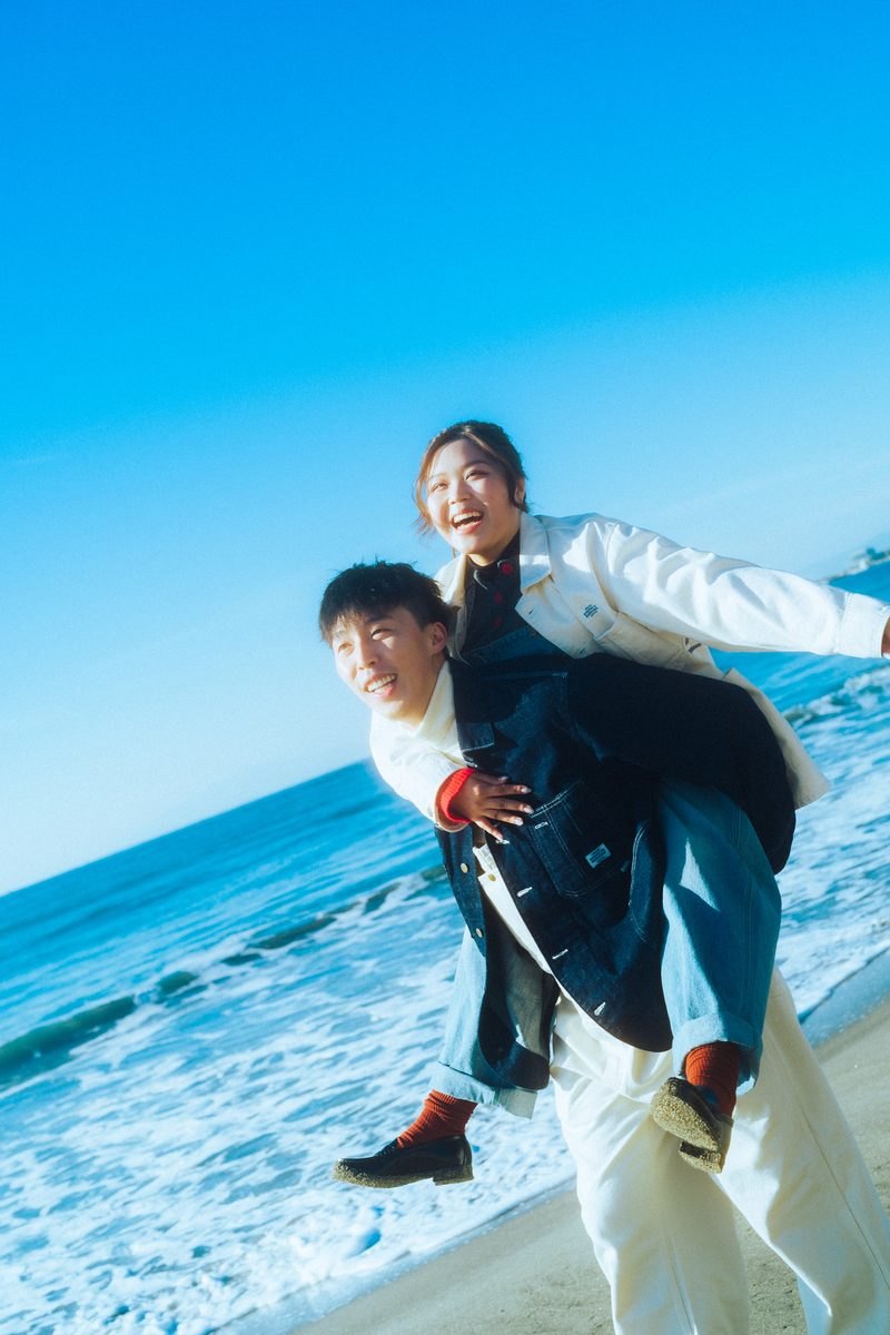海辺でおんぶをして笑うカップル