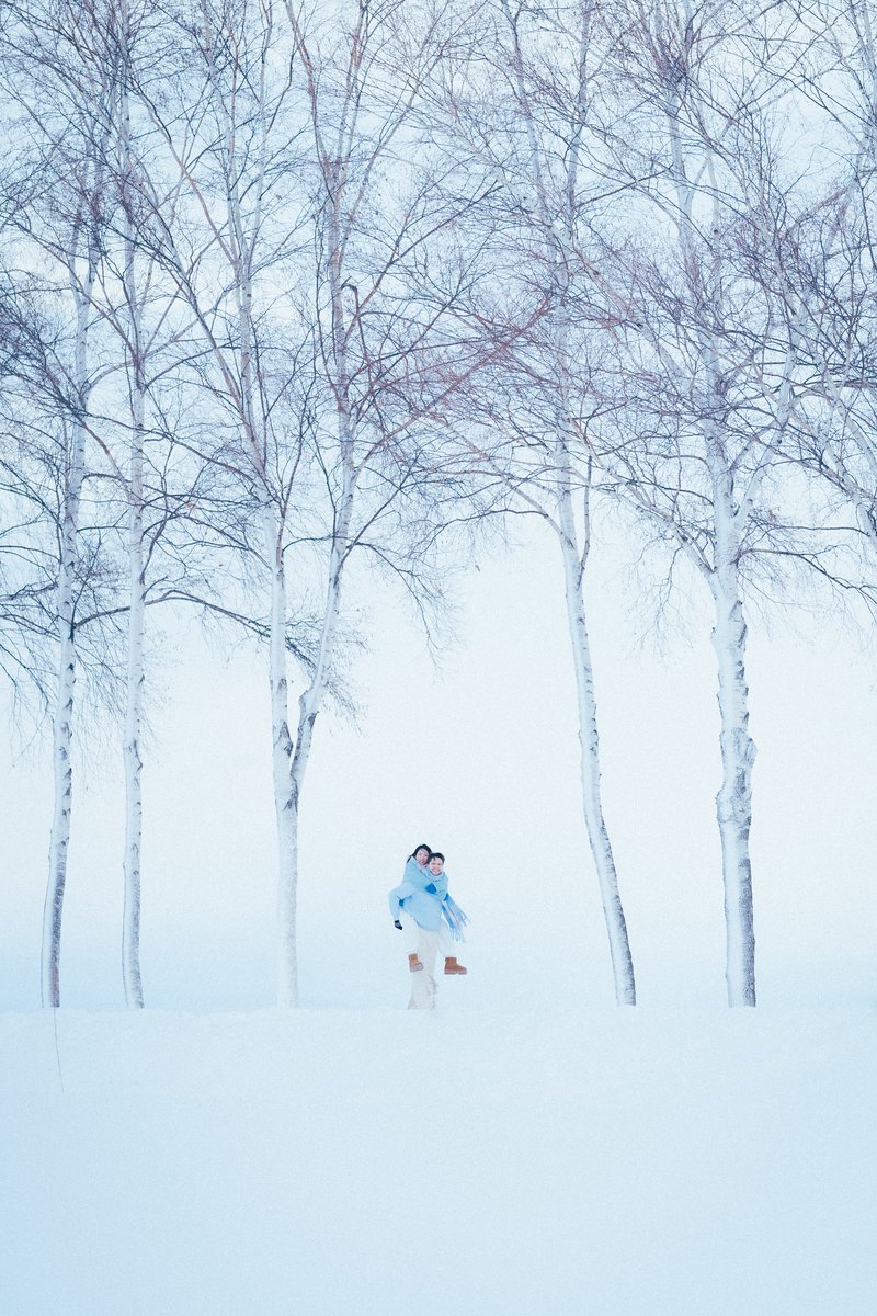 A couple in a snow-covered birch forest